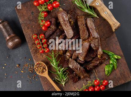 Geröstetes Stück Rinderribeye auf einem braunen Schneidebrett in Stücke geschnitten Stockfoto