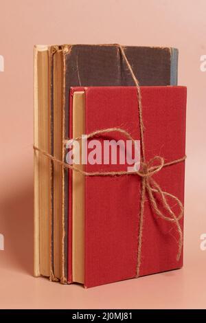 Ein Stapel alte, zerschmetterte Bücher, gefesselt mit einem Juteseil auf einem farbigen Hintergrund Stockfoto