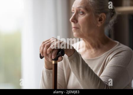 Verärgert einsam grauhaarige ältere Frau hält Spazierstock Stockfoto