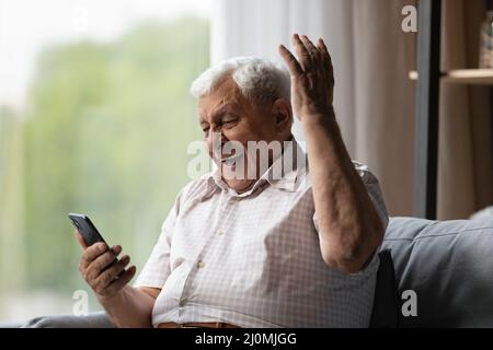 Älterer Mann schaut auf Handy, lesen unglaubliche Nachrichten fühlt sich aufgeregt Stockfoto