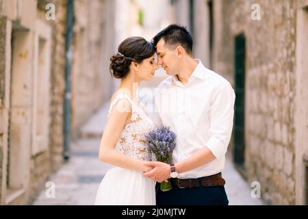 Sibenik, Kroatien - 05.06.17: Bräutigam lehnte seine Stirn mit einem Lavendelstrauß in einem weißen Kleid aga gegen die Stirn der Braut Stockfoto