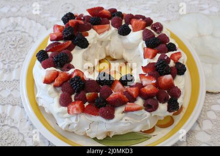 Ein hausgemachtes traditionelles australisches Pavlova-Dessert mit frischer Schlagsahne und Beeren Stockfoto