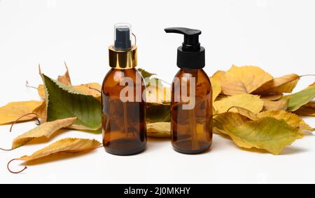 Braune Glasflasche mit schwarzer Pumpe von Kosmetikprodukten auf weißem Tisch. Natürliche Bio-Spa-Kosmetik, Beauty-Konzept Stockfoto