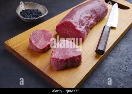 Traditionelles Roh-Rinderfilet-Steak natürlich mit schwarzem Salz als Nahaufnahme auf einem modernen Holzbrett Stockfoto