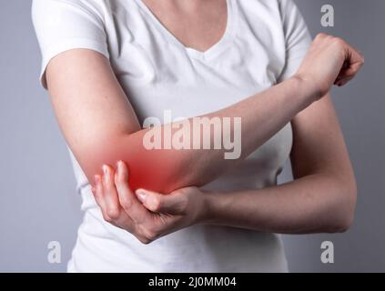 Frau, die unter Ellenbogenschmerzen leidet und schmerzhafte Hände mit einer Nahaufnahme von roten Punkten hält. Handverletzung. Gesundheitsprobleme, Medizin, Behandlungskonzept. Hochwertige Fotos Stockfoto