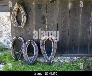 Alte Pferdesalgen, die an einer braunen Holzwand hängen. Mit Pferdebalgen wurde das Tier an einem Wagen oder Pflug befestigt. Stockfoto