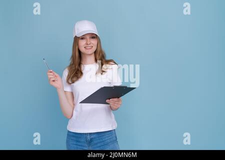 Lieferung Frau Schreiben Dokument isoliert auf blauem Hintergrund in weißem T-Shirt und Mütze. Kaukasische fröhliche Mädchen Mondlicht als Promoter und Berater Stockfoto