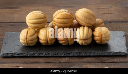 Gebackene Dessertnüsse mit Kondensmilch auf schwarzem Schieferbrett Stockfoto