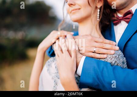 Kotor, Montenegro - 08.06.17: Bräutigam im blauen Anzug umarmt die Braut in einem Spitzenkleid von hinten. Nahaufnahme Stockfoto