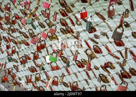 Liebe Vorhängeschlösser mit Herzform. Konzept der Liebe. Metallisches Vorhängeschloss mit Liebe auf einer Brücke voller Vorhängeschlösser. Stockfoto