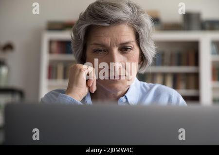 Nahaufnahme einer Frau mittleren Alters, die auf den Laptop starrt Stockfoto