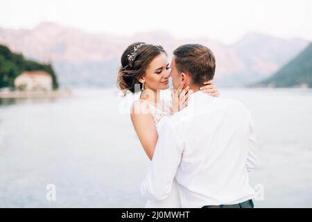 Kotor, Montenegro - 20.06.17: Braut umarmt und küsst sich fast vor der Kulisse der Berge und des Meeres. Nahaufnahme Stockfoto