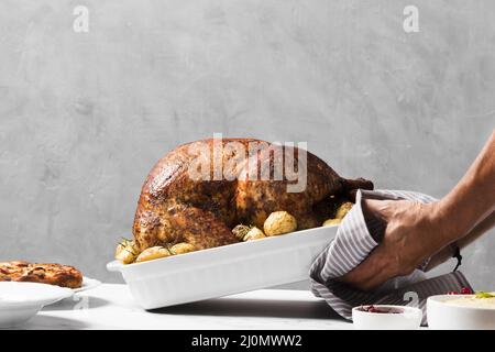 Nahaufnahme der Hände, die den truthahn auf den Tisch legen Stockfoto