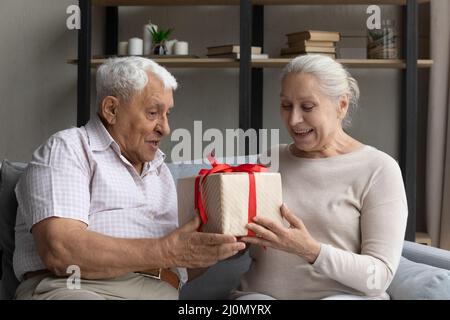 Der ältere Mann gratuliert seiner liebenswerten, heidseligen Frau zum Geburtstag Stockfoto