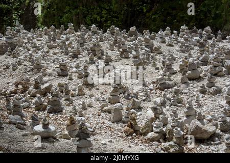 Steintürme und Steinhaufen an einem Flussufer. Gestapelte Felsen bilden Türme. Stockfoto