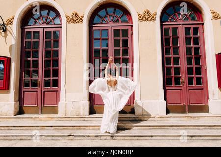 Sibenik, Kroatien - 05.06.17: Braut in einem weißen Kleid flatternd im Wind steht vor hohen Glastüren zu einem alten Bui Stockfoto