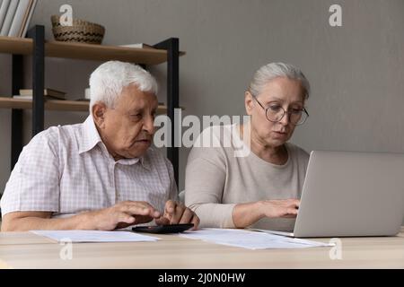 Ehepartner im Alter von schweren Jahren sitzen am Schreibtisch und verwalten die Haushaltsfinanzen Stockfoto