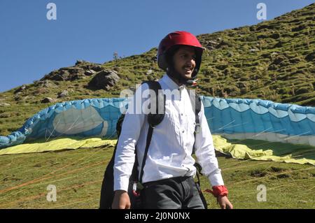 Ein lächelnder junger Mann, der sich auf den Gleitschirmflug vorbereitet Stockfoto