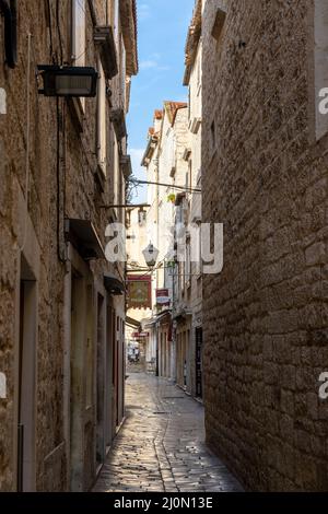 Enge Gasse mit Kopfsteinpflasterstraße und alten Gebäuden im historischen Stadtzentrum von Trogir Stockfoto