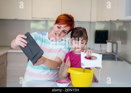 Kleines Mädchen und Mutter machen Tastz Kuchen in kithen Familie Spaß zu Hause Stockfoto