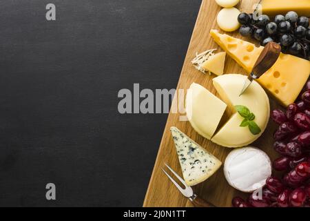 Flache Mischung aus Gourmet-Käse und Trauben auf Schneidebrett mit Kopierfläche Stockfoto