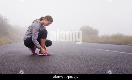 Ich bin bereit, auf die Straße zu gehen. Aufnahme einer jungen Frau, die sich auf einen Lauf vorbereitet. Stockfoto