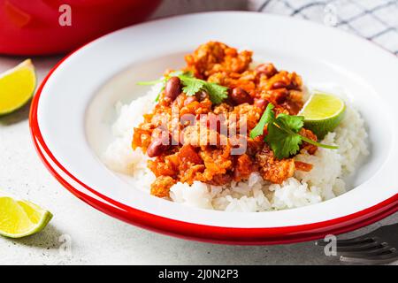 Chili con Carne - Hackfleisch mit Gemüse und Bohnen in Tomatensauce mit Reis auf dem Teller. Mexikanisches Speisekonzept. Stockfoto