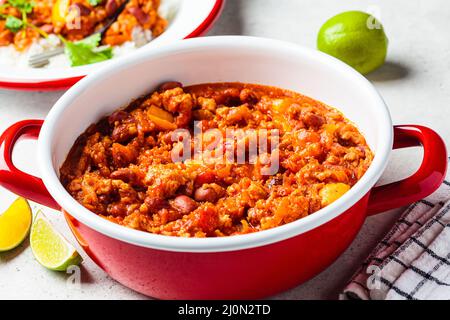Vegane Chili con Carne mit Gemüse und Bohnen in Tomatensauce in rotem Topf. Mexikanisches Speisekonzept. Stockfoto
