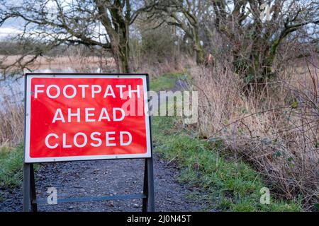 Roter Fußweg vor geschlossenem Warnschild auf einem Landweg Stockfoto