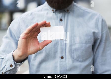 Nahaufnahme der Hand eines Geschäftsmannes, der eine weiße, leere Visitenkarte zeigt Stockfoto