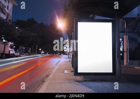 Leere Plakatwand Bushaltestelle Nacht mit Lichtern Autos vorbei Stockfoto