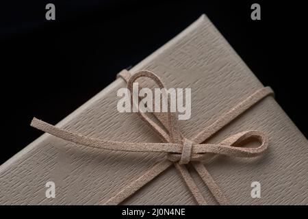 Nahaufnahme der braunen Geschenkbox mit Lederschleife Stockfoto