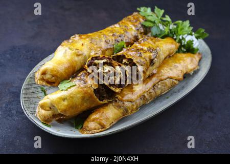 Traditionelle türkische knusprige Sigara borek-Brötchen mit Hackfleisch in Filo-Gebäck gerollt, die als Nahaufnahme in einer nordischen Designplate serviert werden Stockfoto