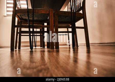 Beine aus Holzstühlen und Holztischen im Vintage- und Retro-Stil. Die Tischbeine sind aus Metall. Alle Stühle und Tische liegen auf Holzboden Stockfoto