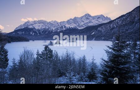 Winter eisgekühlter Eibsee mit verschneiten Bergpanoramalandschaft in Bayern Wettersteingebirge im Morgensonnenlicht Stockfoto