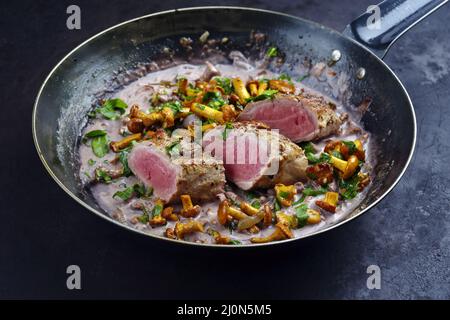 Gebratenes, trocken gealtertes Schweinefilet Chateaubriand Medaillon-Steak, natürlich mit Pfifferlingen in Walnusscreme-Sauce, serviert als Nahaufnahme in einem Stockfoto