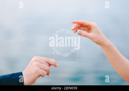 Männliche und weibliche Hand mit einem transparenten Bild, das einen Kranz zeigt Stockfoto