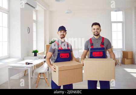 Männliche Lader mit Pappkartons in den Händen helfen dem Kunden, in ein neues Zuhause zu ziehen. Stockfoto