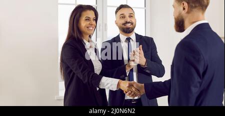 Zufrieden lächelnde Geschäftspartner bestätigen ihre erfolgreiche Vereinbarung mit dem Händedruck. Stockfoto