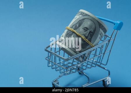 In einen Schlauch gerollte Dollars liegen in einem Einkaufskorb. Stockfoto