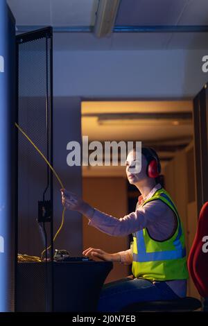 Kaukasische Ingenieurin berührt einen Draht im Computerserverraum Stockfoto
