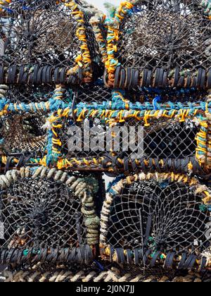 Gestapelte Krabben- und Hummer-Töpfe in Nahaufnahme an einem der Kais im Seahouses Harbour an der Nordostküste Englands. Stockfoto