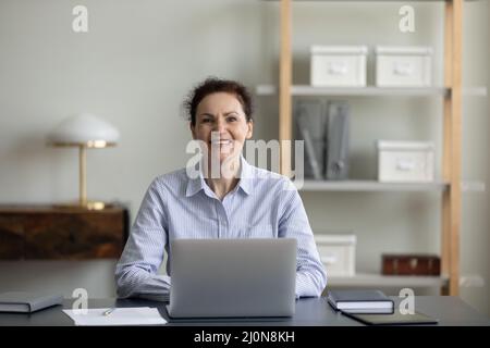 Glückliche Geschäftsfrau, die am Arbeitsplatz sitzt Stockfoto