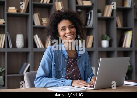 Glücklich Student Mädchen in lässig sitzen am Schreibtisch mit Laptop Stockfoto