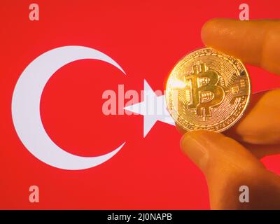 Mit einem physischen goldenen Bitcoin über der türkischen Flagge. Die Türkei als Investor in Kryptowährung und Blockchain-Technologie. Finanzieller Hintergrund Stockfoto