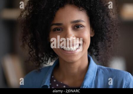 Fröhliches Mädchen, das mit einem toothy Lächeln auf die Kamera schaut Stockfoto