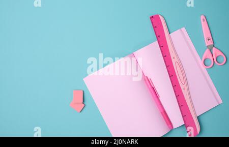 Offenes Notizbuch mit rosafarbenen Blättern, Schere und Lineal auf blauem Hintergrund, Draufsicht Stockfoto