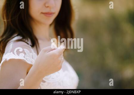 Braut in einem weißen Kleid hält eine Heuschrecke an der Hand. Hochformat Stockfoto