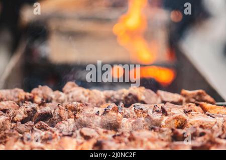 Schweinefleisch Spieß, gegrillt oder gebraten in einem Grill auf einem offenen Feuer und Flammen, Schaschlik oder Schaschlyk für ein Picknick mit Mistgabeln, aus der Nähe Stockfoto