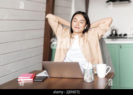 Arbeit von zu Hause und Fernunterricht Konzept. Junge asiatische Mädchen fertig Online-Kurs, Stretching und legte sich zurück auf Stuhl, restin Stockfoto